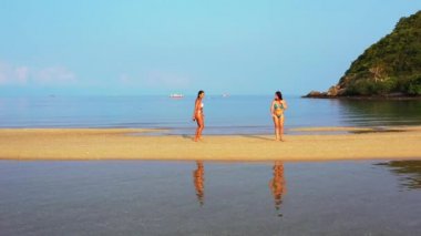 Deniz kıyısında dinlenen bikinili iki genç kız arkadaş. Tropik tatil beldesinde güzel kadınlar    
