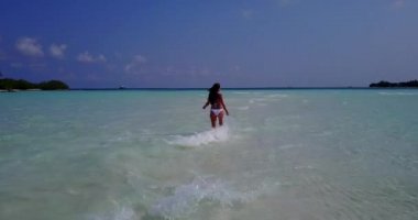 Bora Bora 'daki tropikal sahilde beyaz bikini giyen ve dinlenen genç bir kadın.