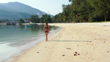 Tropik adanın kıyılarında mayo giymiş güzel genç bir kadının videosu. 