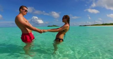 Deniz suyunda duran genç adam ve kadın. Tropik bir tatil köyünde dinlenen güzel bir çift.    