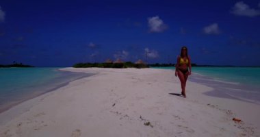 Bikini giyen, deniz tırpanı üzerinde yürüyen, bir şey düşünen bronz tenli kızın videosu. 