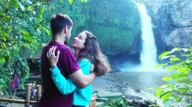 Güzel kız, erkek arkadaşıyla şelalenin yanında iyi vakit geçiriyor. Seyahat konsepti görüntüleri. 