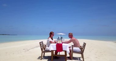 Çiftler tropikal bir plajda özel bir yemek yiyorlar.