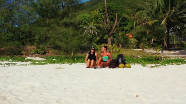 Δύο Νεαρές Φίλες Κάθονται Στην Αμμώδη Ακτή Τσάντες Δίπλα Τους — Αρχείο Βίντεο