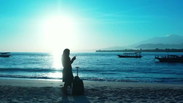 Silhueta Mulher Com Mala Praia Usando Smartphone Pôr Sol — Vídeo de Stock
