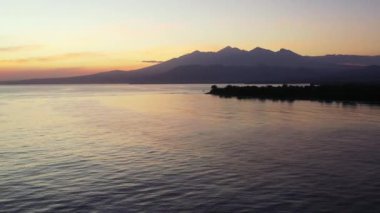 Deniz kenarında sakin bir günbatımı ve dağ arkası. Endonezya, Bali 'ye tropikal yolculuk.