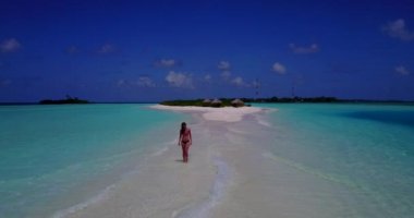 Bikini giyen, deniz tırpanı üzerinde yürüyen, bir şey düşünen bronz tenli kızın videosu. 