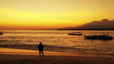 Gün batımında sahilde bir kadın silueti