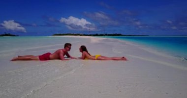 Genç bir adam ve kadın deniz kıyısında güneşleniyorlardı. Tropik bir tatil köyünde dinlenen güzel bir çift.   