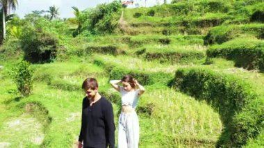 Erkek arkadaşıyla birlikte tropik adanın yeşil tarlasında yürüyen genç ve güzel bir kız. Romantik bir çift tatilin tadını çıkarıyor.  