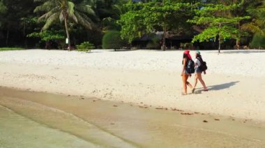 Sahilde yürüyen iki bayan arkadaşın görüntüsü. 