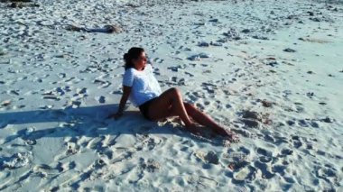 Kız kumsalda oturuyor ve dinleniyor.