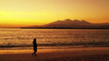 Gün batımında sahilde bir kadın silueti