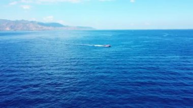 Turkuaz deniz suyunda kayıktaki adamın hava görüntüsü.