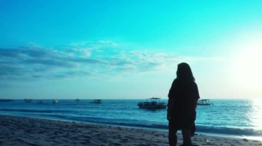 Kumsalda sırt çantalı bir kadın.