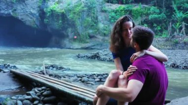 Romantik iki turist, şelale ve nehir kenarında birlikte duruyorlar.   