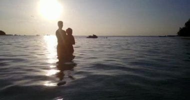 Genç çift Tayland 'da gün batımında plajda dinleniyor..