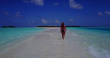 Bikini giyen, deniz tırpanı üzerinde yürüyen, bir şey düşünen bronz tenli kızın videosu. 