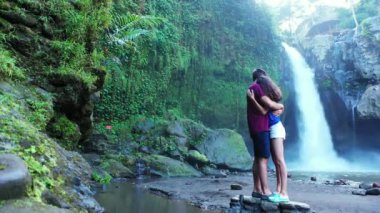 Romantik turistlerin, şelalenin yanında yan yana durdukları bir video.  