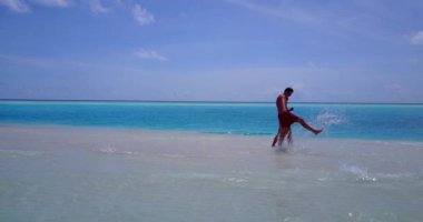 Genç bir adam ve kadın deniz suyunda yürüyorlar. Tropik bir tatil köyünde dinlenen güzel bir çift.    