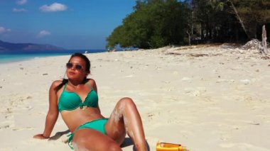 Tropik plajda güneşlenen güzel genç bir kadın.