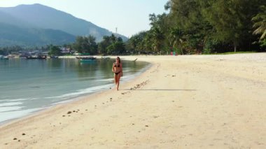 Tropik adanın kıyılarında mayo giymiş güzel genç bir kadının videosu. 