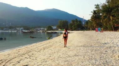 Sahilde yürüyen kulaklıklı bir kadın ve soğuk yaz gezisi konsepti. 