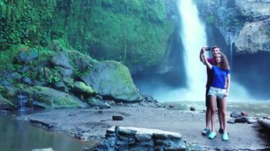 Romantik turistlerin, şelalenin yanında yan yana durdukları bir video.  