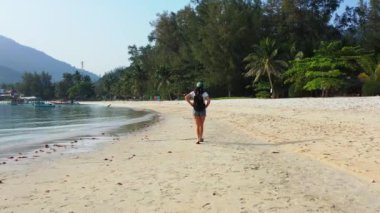 Sırt çantalı kadın turist tropik ada sahillerinde yürüyor, yaz tatili konsepti  