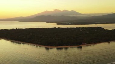 Arka planda dağlar olan deniz kenarında gün batımı. Bahamalar Doğası, Karayipler.