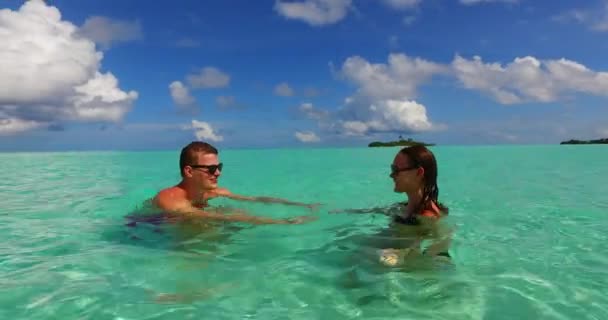 若い男性と女性の海の水で泳いでいます 美しいカップルは熱帯リゾートに休みます — ストック動画