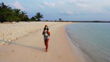 Kumsalda yürüyen maskeli bir kızın görüntüsü. 