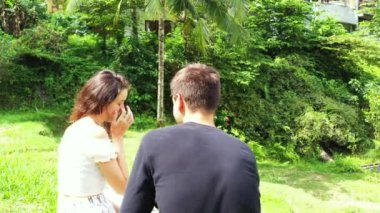 Erkek arkadaşıyla çimenlerde oturan çekici genç bir kadın, seyahat konsepti görüntüleri. 