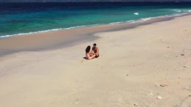  Kumsalda bir çiftin videosu. Kadın ve adam karşı karşıya oturuyor.