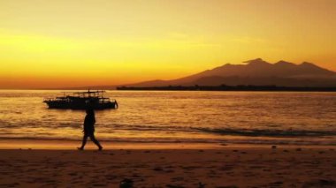 Gün batımında sahilde bir kadın silueti