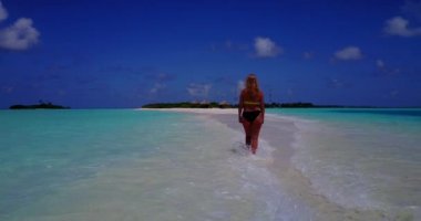 Bikini giyen, deniz tırpanı üzerinde yürüyen, bir şey düşünen bronz tenli kızın videosu. 