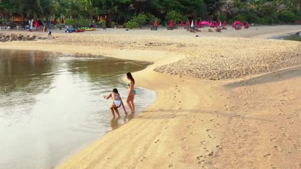 两个穿着比基尼的年轻女友躺在海滨的水里 美丽的女人在热带度假胜地休息 — 图库视频影像
