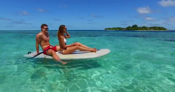 若い男と女は海のサーフボードで泳ぐ 美しいカップルは熱帯リゾートに休みます — ストック動画