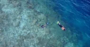 Genç adam ve kadın turkuaz denizde şnorkelle yüzüyorlar. Tropik bir tatil köyünde dinlenen güzel bir çift.    