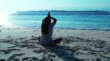 Kız kumsalda oturuyor ve yoga yapıyor.