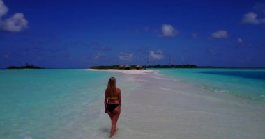 Bikini giyen, deniz tırpanı üzerinde yürüyen, bir şey düşünen bronz tenli kızın videosu. 