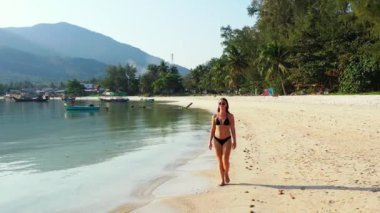 Tropik adanın kıyılarında mayo giymiş güzel genç bir kadının videosu. 