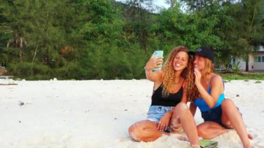 Gülümseyen çekici genç bayan arkadaşlar tropik adanın sahilinde tatilin tadını çıkarıyorlar, yaz yolculuğu konsepti görüntüleri. 