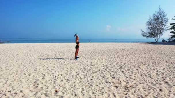Frau mit Bräune beim Kurzhanteltraining in Meeresnähe am Sandstrand der Insel, Sommerfreizeitkonzept 