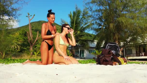 Two Young Girl Friends Sitting Sandy Sea Coast Sundbathing Talking — Stock Video