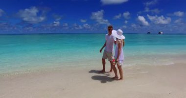 Genç bir adam ve kadın kumsalda yürüyor. Tropik bir tatil köyünde dinlenen güzel bir çift.    