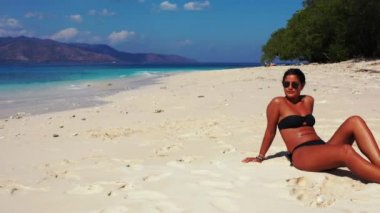 Tropik plajda güneşlenen güzel genç bir kadın.