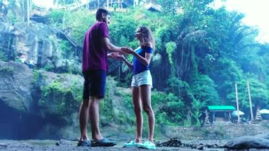 Romantik iki turist, şelale ve nehir kenarında birlikte duruyorlar.   