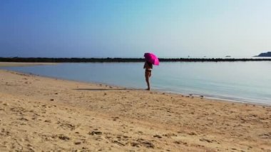 Siyah bikinili genç çekici kız kumlu sahilde yürüyor, yaz tatili konsepti  