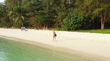 Kumsalda yürüyen maskeli bir kızın görüntüsü. 